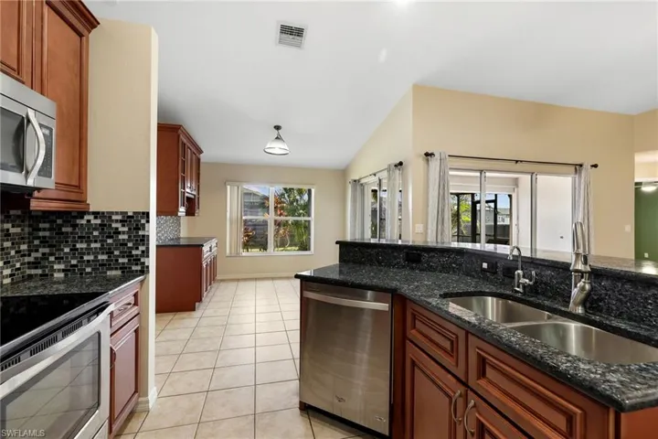 Kitchen featuring dark stone countertops, sink, stainless steel appliances, and plenty of natural light