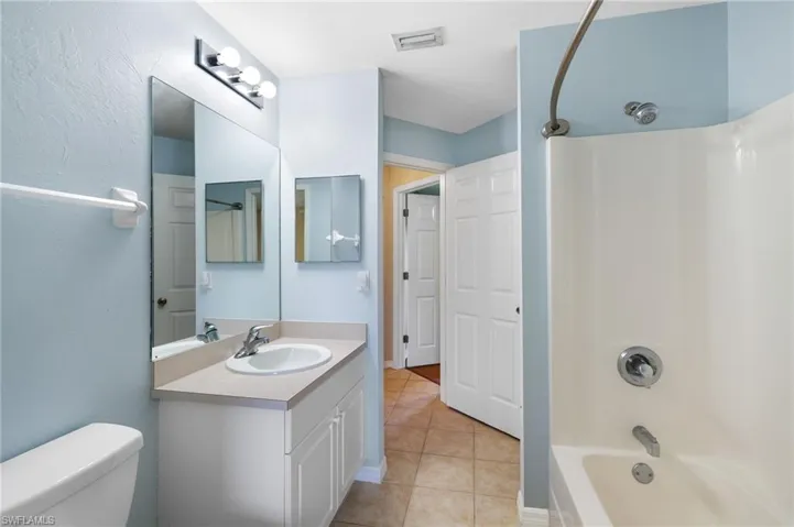 Full bathroom with tile patterned flooring, vanity, toilet, and shower / washtub combination