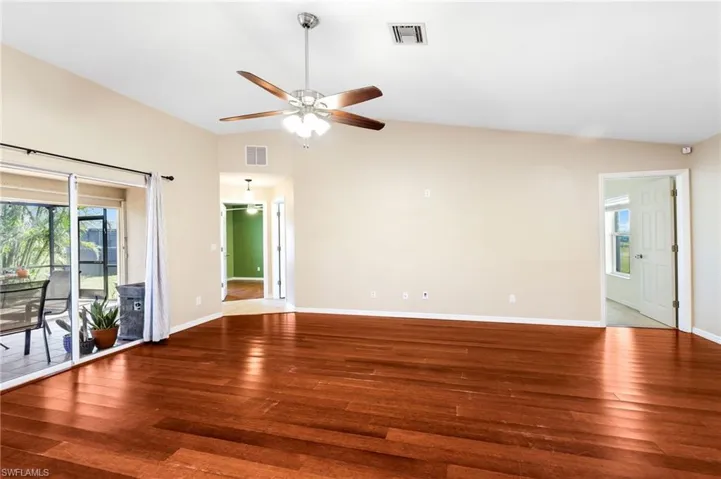 Empty room with hardwood / wood-style flooring, vaulted ceiling, and ceiling fan