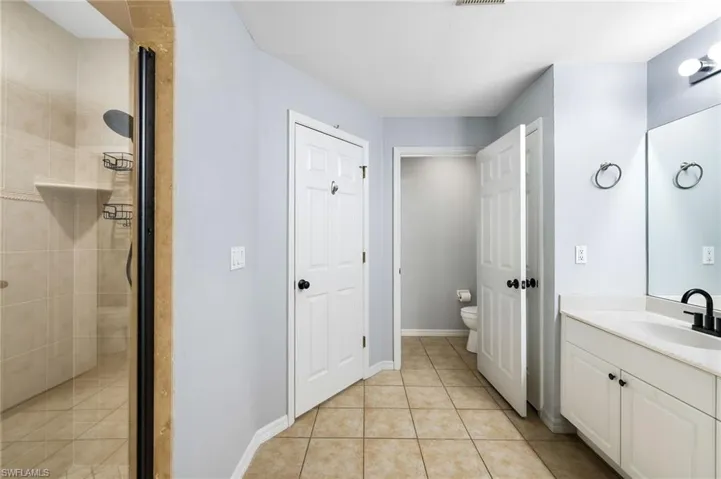 Bathroom featuring tile patterned floors, vanity, toilet, and a shower with shower door