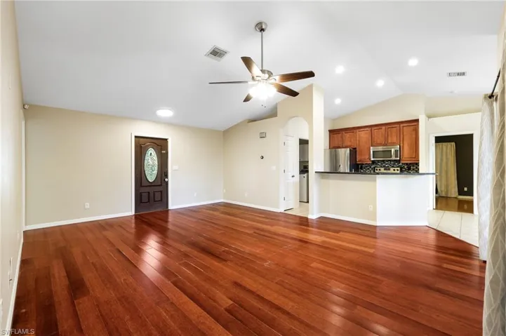 Unfurnished living room featuring hardwood / wood-style floors, vaulted ceiling, and ceiling fan