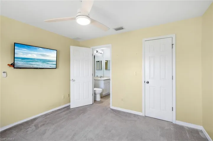 Unfurnished bedroom with light colored carpet, ensuite bath, ceiling fan, and sink