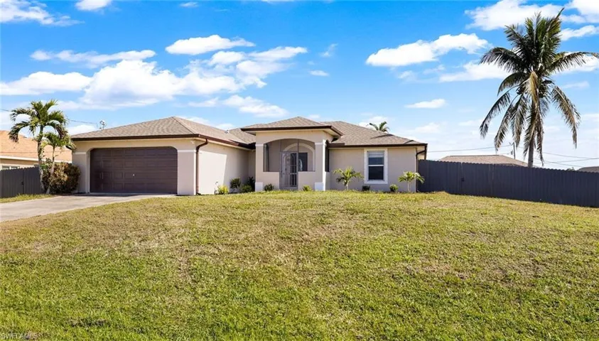View of front of home with a front yard and a garage