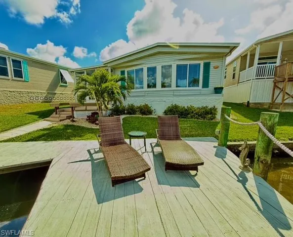 Back of house with a lawn and a wooden deck