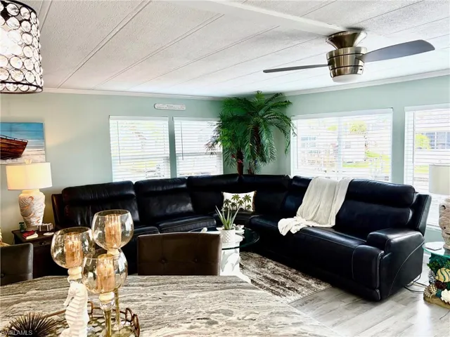 Living area featuring ornamental molding, wood finished floors, a textured ceiling, healthy amount of natural light, and ceiling fan