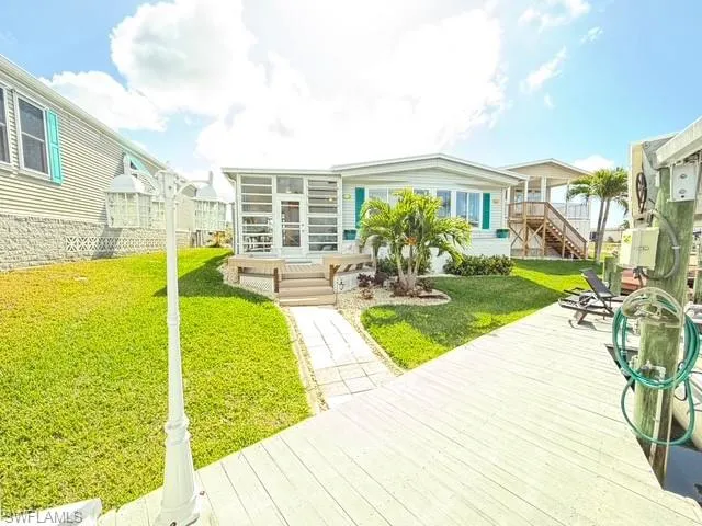 Rear view of house with a wooden deck and a lawn