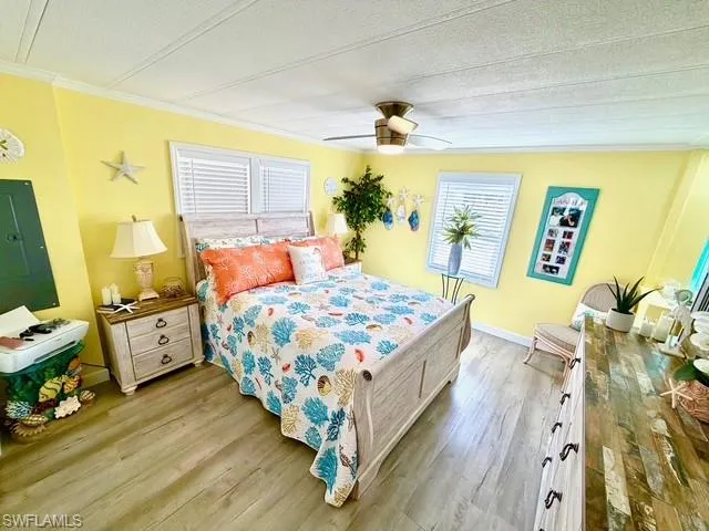 Bedroom featuring electric panel, light wood-style flooring, ceiling fan, a textured ceiling, and ornamental molding