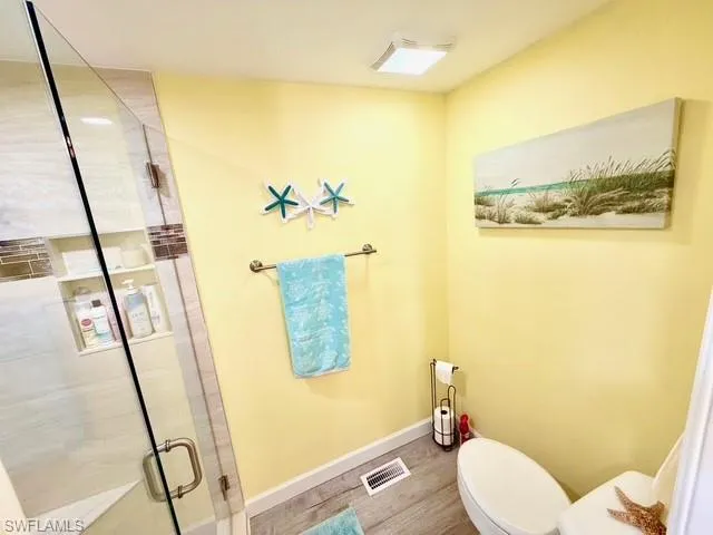 Bathroom featuring a shower stall and wood finished floors