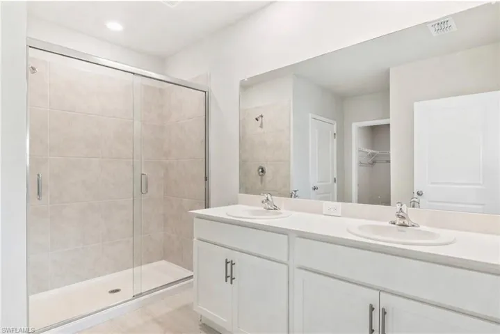 Full bath with a spacious closet, double vanity, and a stall shower