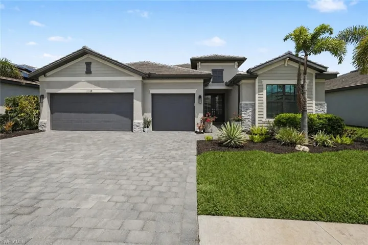 Modern facade with a paver driveway, two-car garage, and a lush lawn