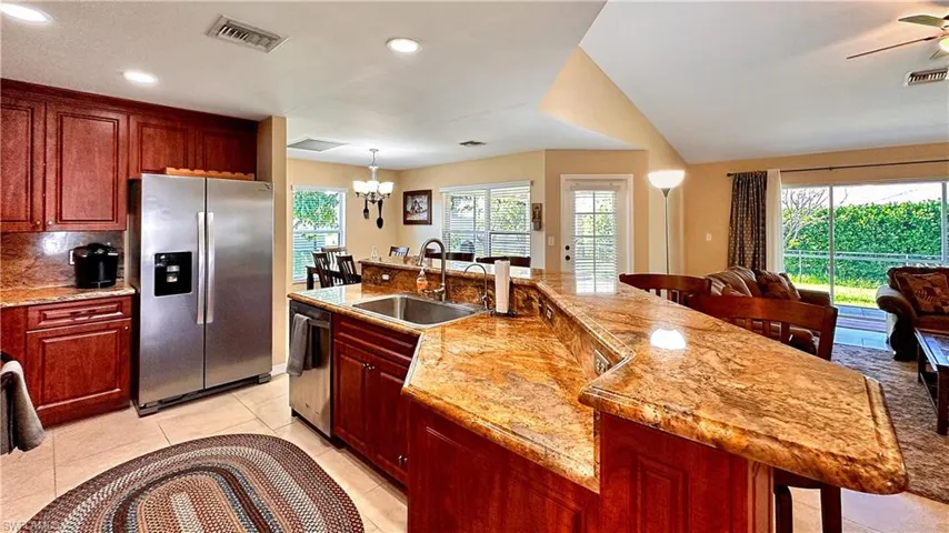 Kitchen with a large island, ceiling fan with notable chandelier, appliances with stainless steel finishes, decorative light fixtures, and sink