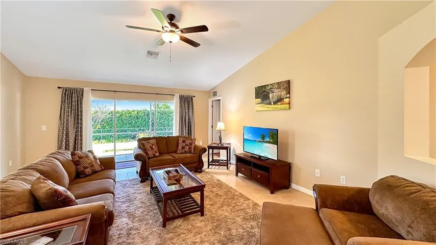 Tiled living room featuring high vaulted ceiling and ceiling fan