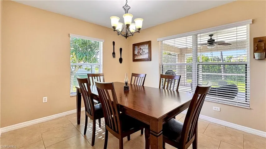 Tiled dining space featuring ceiling fan with notable chandelier