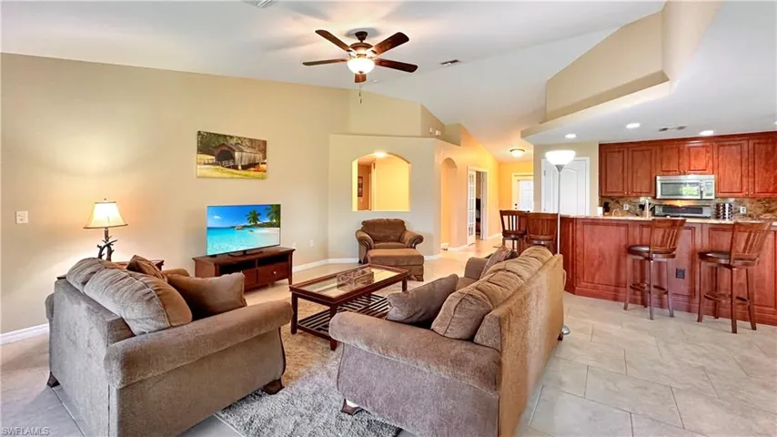 Tiled living room featuring ceiling fan and high vaulted ceiling