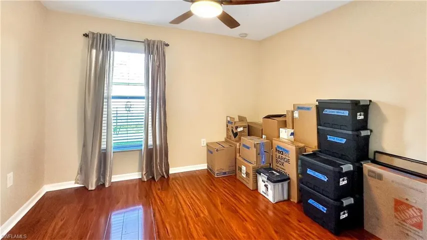 Home office with dark wood-type flooring and ceiling fan