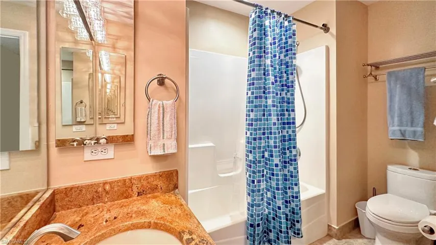 Full bathroom featuring shower / bathtub combination with curtain, sink, tile patterned flooring, and toilet