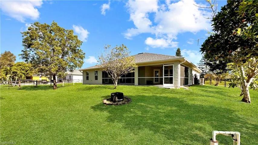 Rear view of property featuring central AC, a sunroom, and a yard