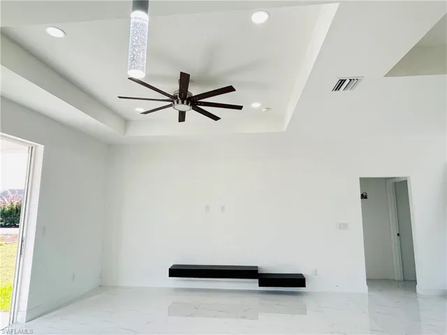 Living room with a ceiling fan, light marble finish flooring, a raised ceiling, and recessed lighting