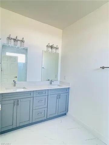 Bathroom featuring double vanity and light marble finish floors
