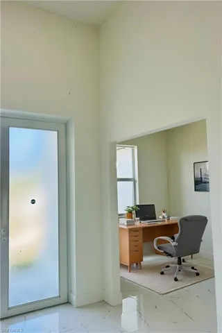 Virtually staged office featuring light marble finish floors and a high ceiling