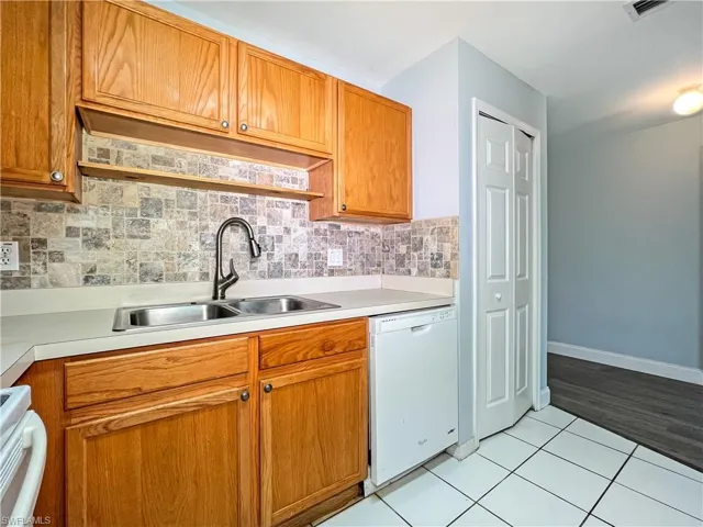 Kitchen with white appliances, light countertops, light tile patterned floors, and wood finish cabinets