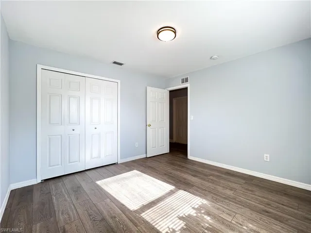 Unfurnished bedroom featuring dark wood-style flooring and a closet