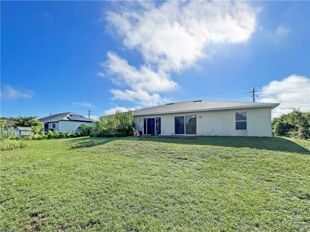 Back of property with a lawn and stucco siding