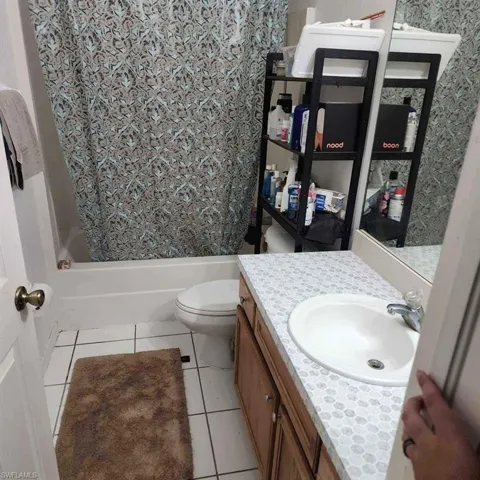 Bathroom featuring vanity, light tile patterned floors, and shower / bath combo with shower curtain