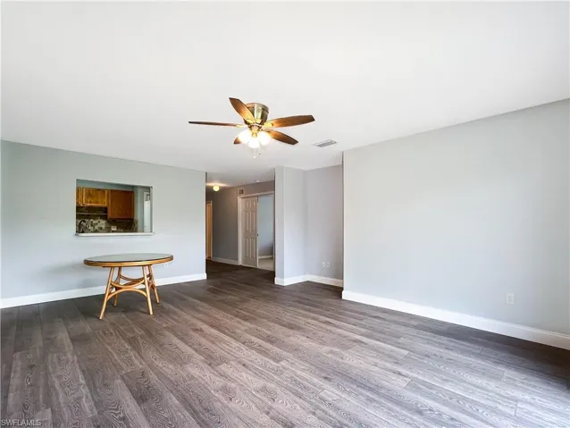 Unfurnished living room featuring dark wood-type flooring and ceiling fan