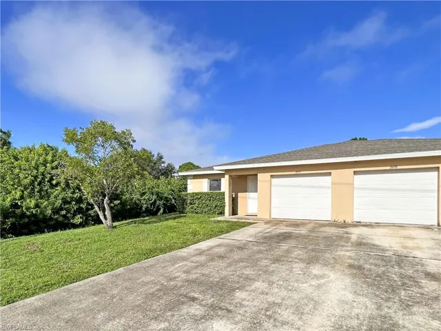 Ranch-style house with concrete driveway, stucco siding, an attached garage, a front lawn, and roof with shingles