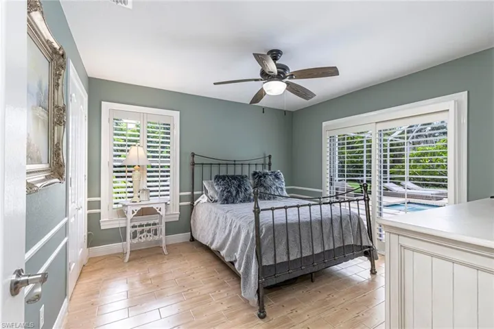 Light wood-finish flooring, a ceiling fan, and plantation shutters feature prominently in this room with direct outdoor access