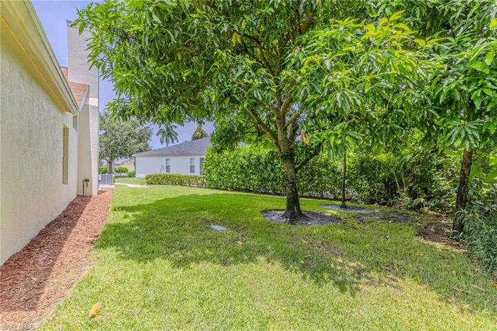 Expansive green lawn with mature trees and perimeter shrubbery