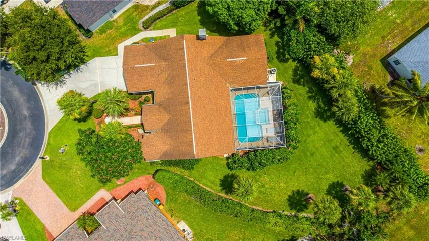 Aerial perspective showcasing the property with a private pool, screened enclosure, and extensive green space