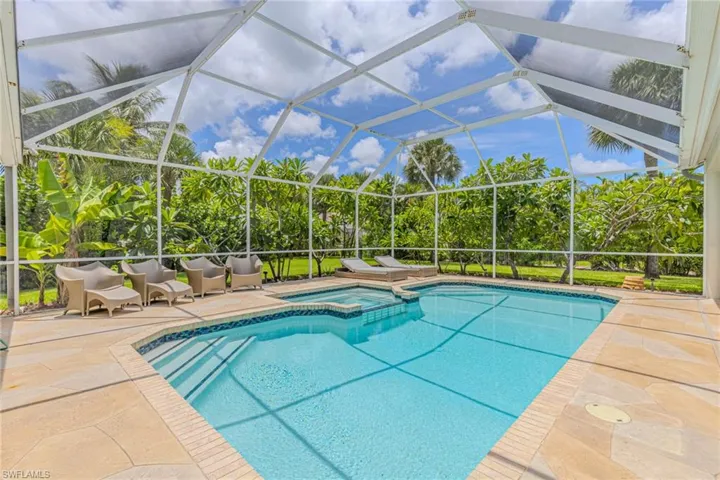 Screened pool enclosure featuring a multi-level swimming pool with integrated spa and light-toned paver decking