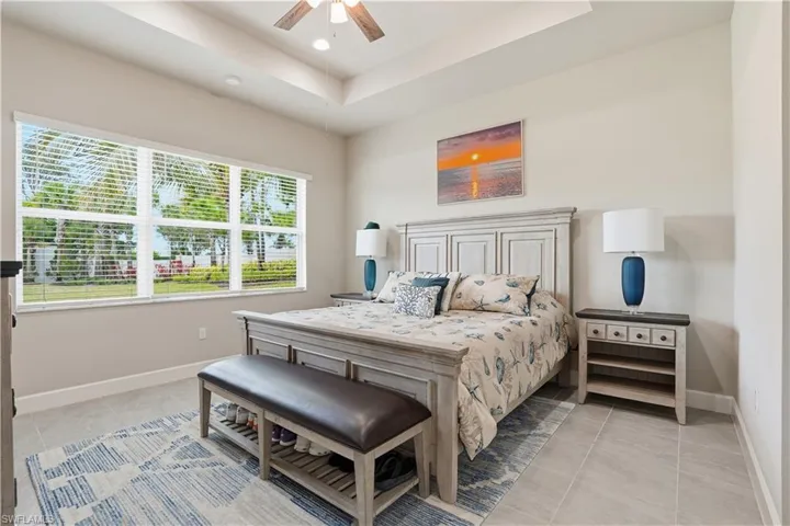 Bedroom featuring a raised ceiling, light tile patterned floors, a ceiling fan, and recessed lighting