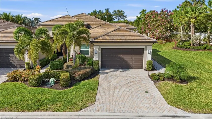 View of front facade with a front lawn, a garage, decorative driveway, stucco siding, and a tiled roof
