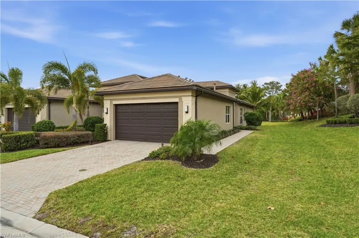 View of front of property with a front yard, stucco siding, decorative driveway, and a garage