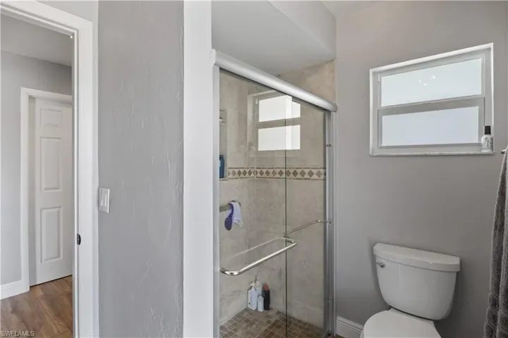 A spacious walk-in shower features glass sliding door providing a luxurious, open feel,