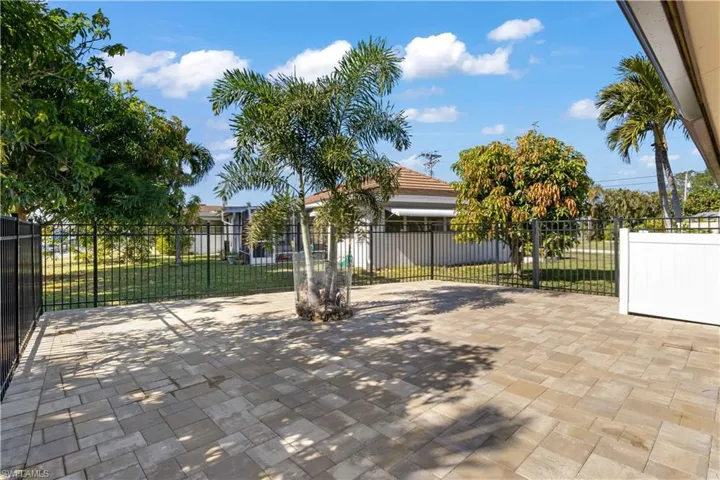 The side of the home is bordered by a privacy fence, with pavers creating a tidy, inviting pathway.