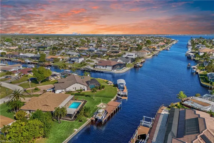 Breathtaking aerial view of the backyard oasis—sparkling pool, lush landscape, extended dock, and wide water views with direct Gulf access!