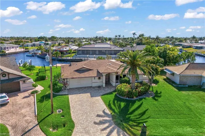 Stunning aerial view of this beautifully remodeled home—spacious front yard, lush landscaping, and incredible water views just steps away!