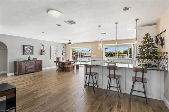 The open layout flows seamlessly into the dining space, all framed by large windows that showcase tranquil views of the pool and canal, creating the perfect setting for everyday meals or elegant entertaining.