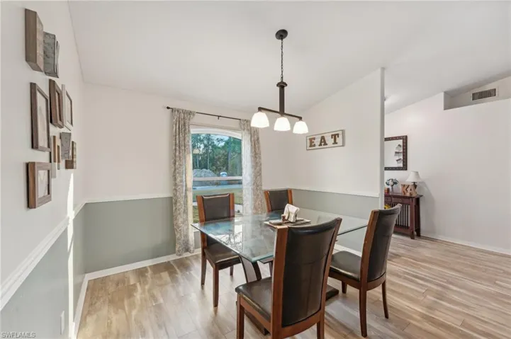Dining room with light hardwood / wood-style flooring and vaulted ceiling