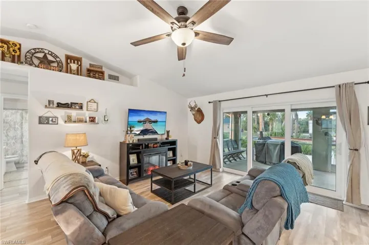 Living room featuring ceiling fan, light hardwood / wood-style floors, and vaulted ceiling