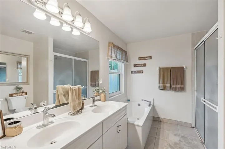 Full bathroom featuring tile patterned flooring, vanity, toilet, and plus walk in shower
