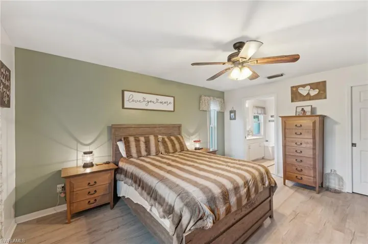 Bedroom with ensuite bath, ceiling fan, and light hardwood / wood-style floors