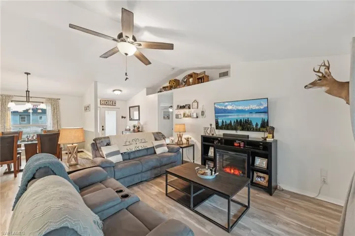 Living room featuring ceiling fan, vaulted ceiling, and light wood-type flooring