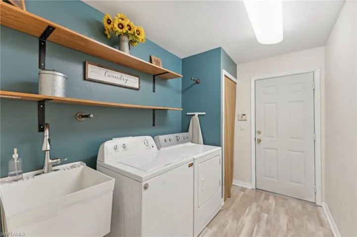 Washroom featuring washer and clothes dryer, light hardwood / wood-style flooring, and sink