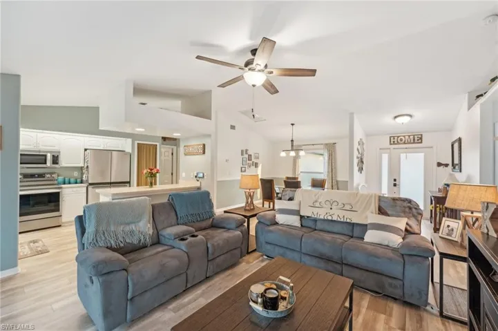 Living room featuring light wood-type flooring, ceiling fan, and lofted ceiling