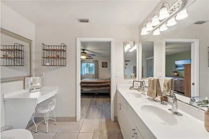 Bathroom featuring tile patterned floors, ceiling fan, a shower with shower door, and vanity